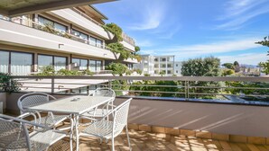 A balcony with a table and chairs, overlooking a residential area with buildings and greenery. - Il Sogno Apartments (Desenzano del Garda)