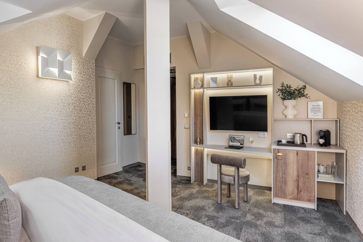 Une chambre d’hôtel moderne équipée d’un grand lit, d’un bureau avec un ordinateur et d’une télévision.