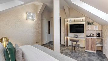 Una moderna camera d'albergo con un letto grande, una scrivania con un computer e una TV.