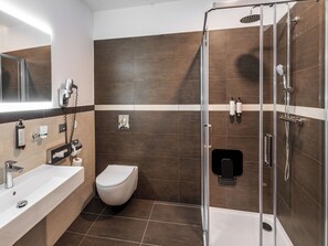 Deluxe kamer | Badkamer | Een douche, een haardroger, een bidet, handdoeken