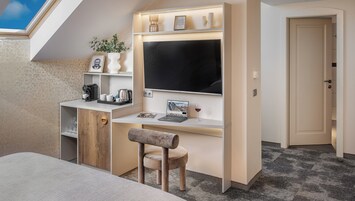 Quarto compacto e moderno com claraboia, uma escrivaninha com um laptop, uma cadeira e uma mesinha de cabeceira.