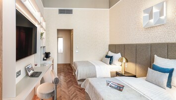Camera d'albergo con due letti, una scrivania con un portatile, una TV e un piccolo angolo salotto.
