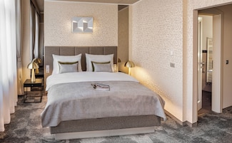 Camera d'albergo con un letto grande, due lampade da comodino, un comodino e un punto luce a parete.