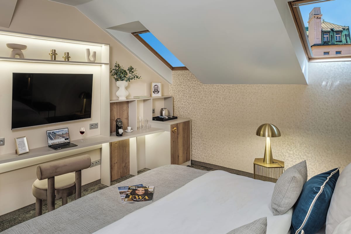 Une chambre moderne avec une lucarne, un lit, un bureau avec un ordinateur portable, une télévision et une machine à café.