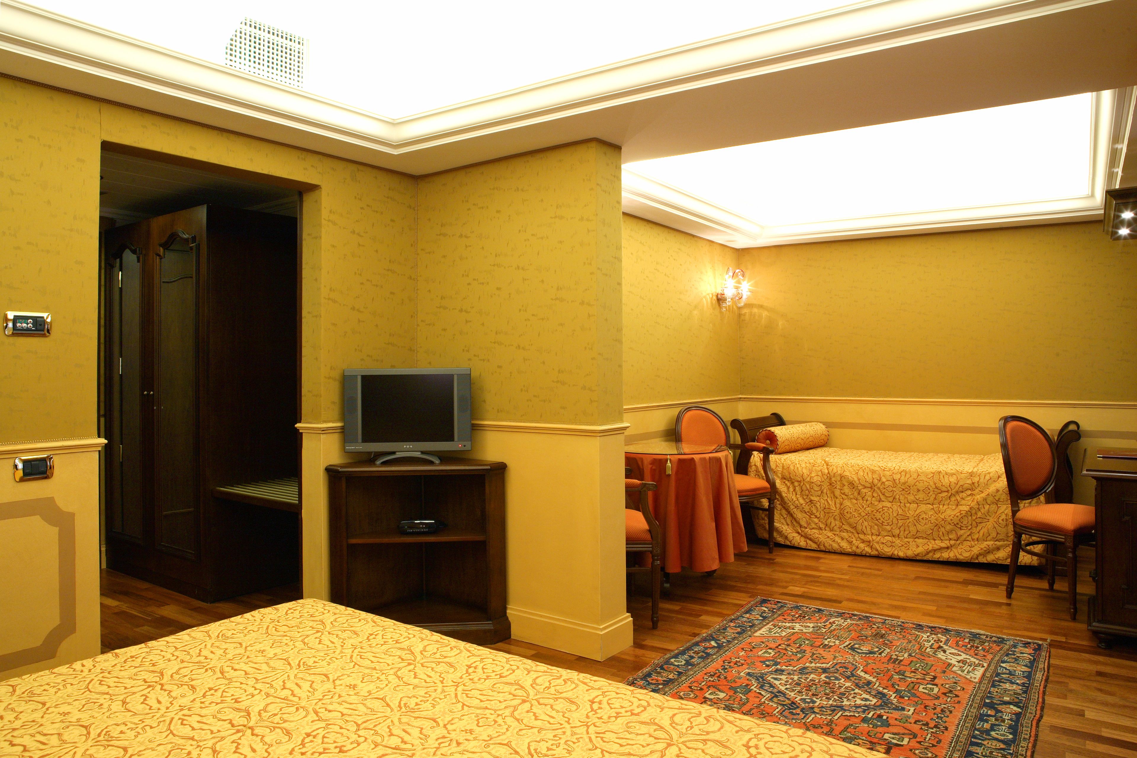 Habitación de hotel con cama, televisión, escritorio y silla. Se ve el cielo por la ventana.