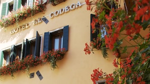 A hotel facade with multiple windows, some with shutters, and balconies adorned with red flowers. - Hotel Al Codega (Venice)