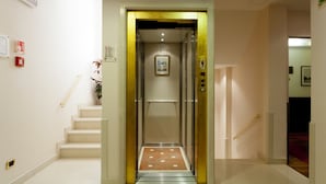 An elevator with a metallic interior and a framed picture on the wall. - Hotel Al Codega (Venice)