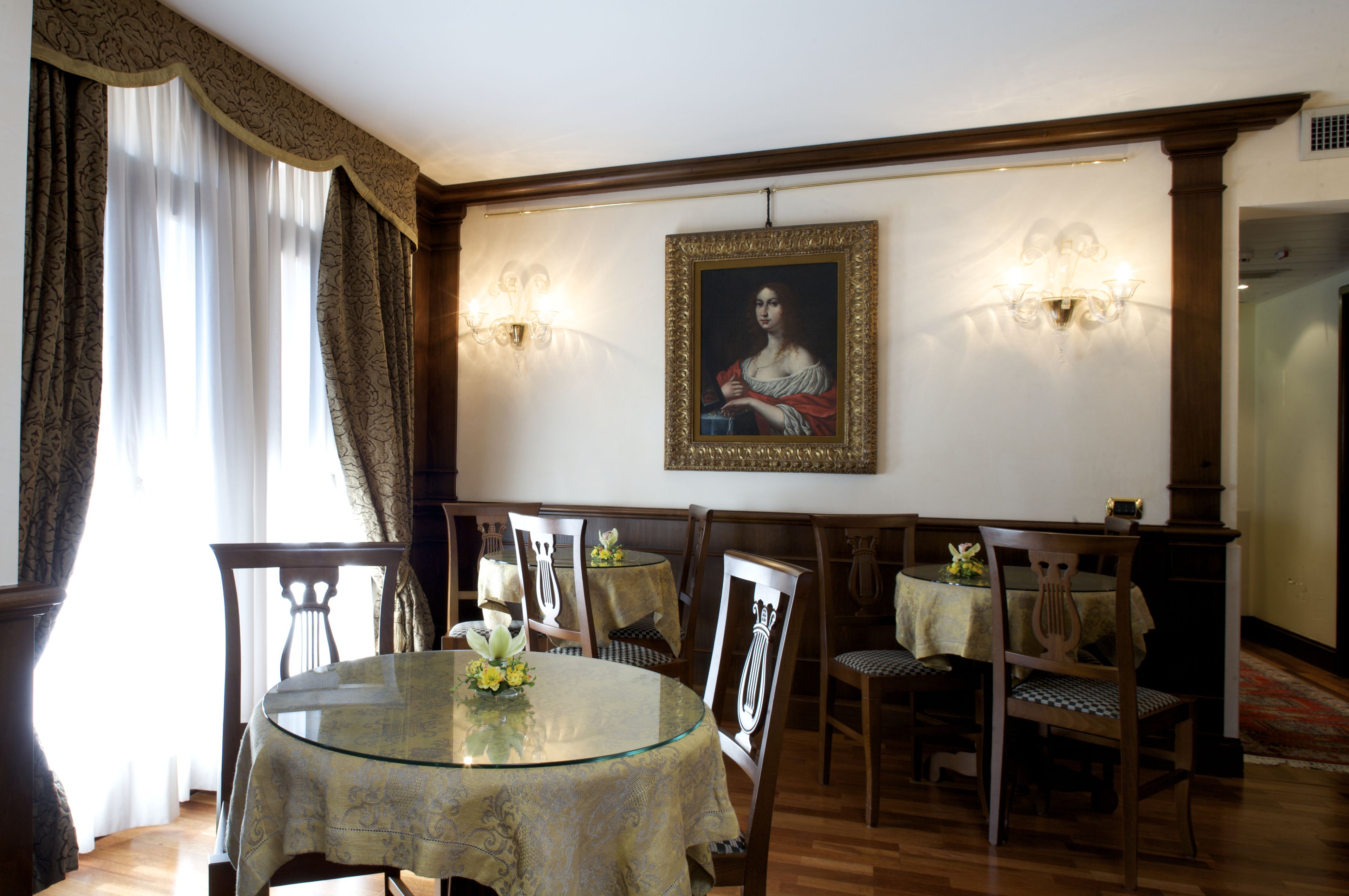 Zona pranzo con tavolo in vetro, sedie e un quadro incorniciato al muro.