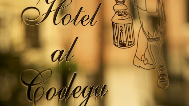 A hotel sign with a drawing of a man holding a lantern. - Hotel Al Codega (Venice)