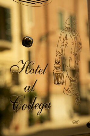 A hotel sign with a drawing of a man holding a lantern. - Hotel Al Codega (Venice)