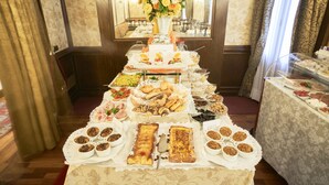 A buffet table with various food items and a centerpiece of flowers. - Hotel Al Codega (Venice)