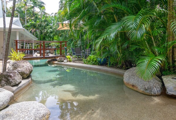 Een buitenzwembad, ligstoelen bij het zwembad