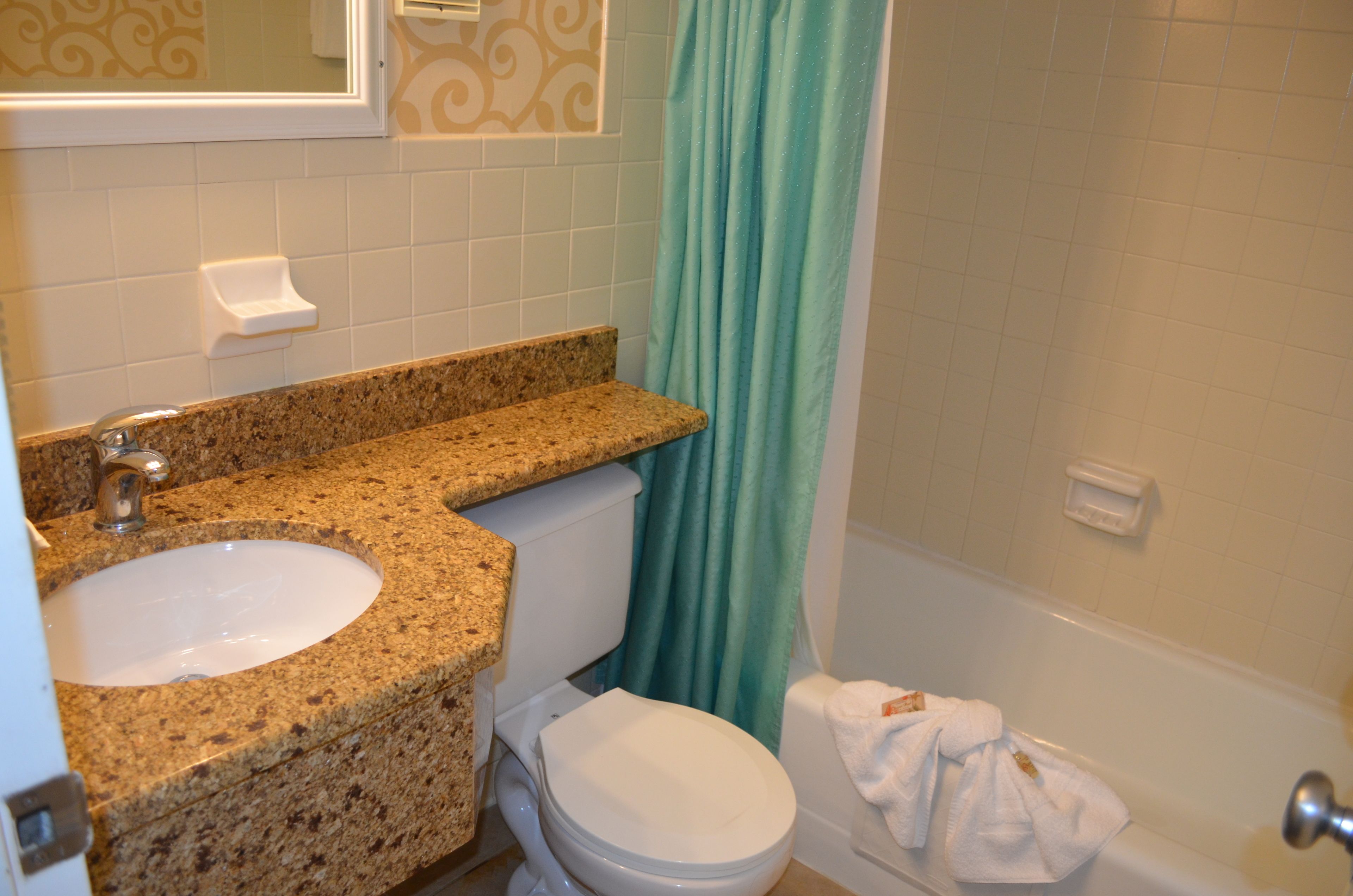 A bathroom with a granite countertop sink, a toilet, and a bathtub.