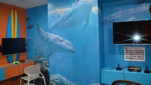 Habitación de acuario con un gran mural de ballenas, un televisor de pantalla plana y una computadora.