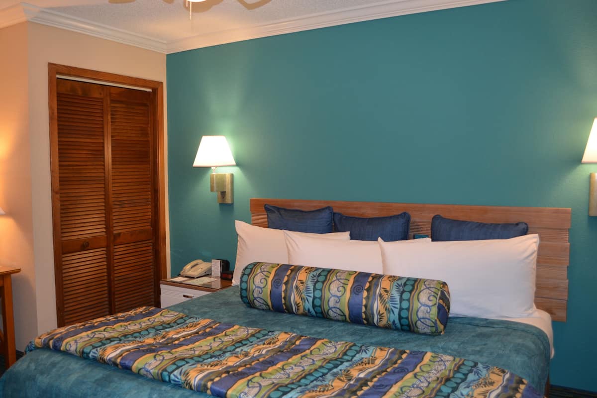 A bedroom with a teal wall, wooden headboard, and a patterned bedspread.