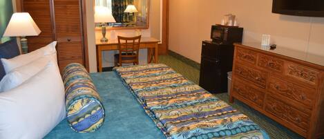 A hotel room with a bed, a desk, a chair, a dresser, a television, and a mirror.