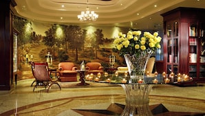 Un vestíbulo con candelabro, área de estar y un jarrón decorativo con flores.