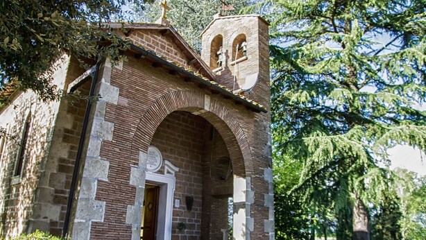 Un pequeño edificio de ladrillo con un arco central y un campanario.