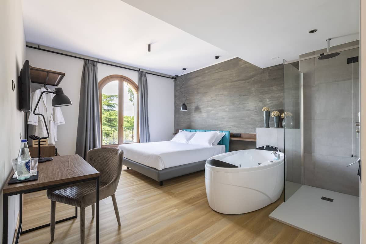 Una habitación de hotel moderna con cama, escritorio, una silla, bañera y zona de ducha.