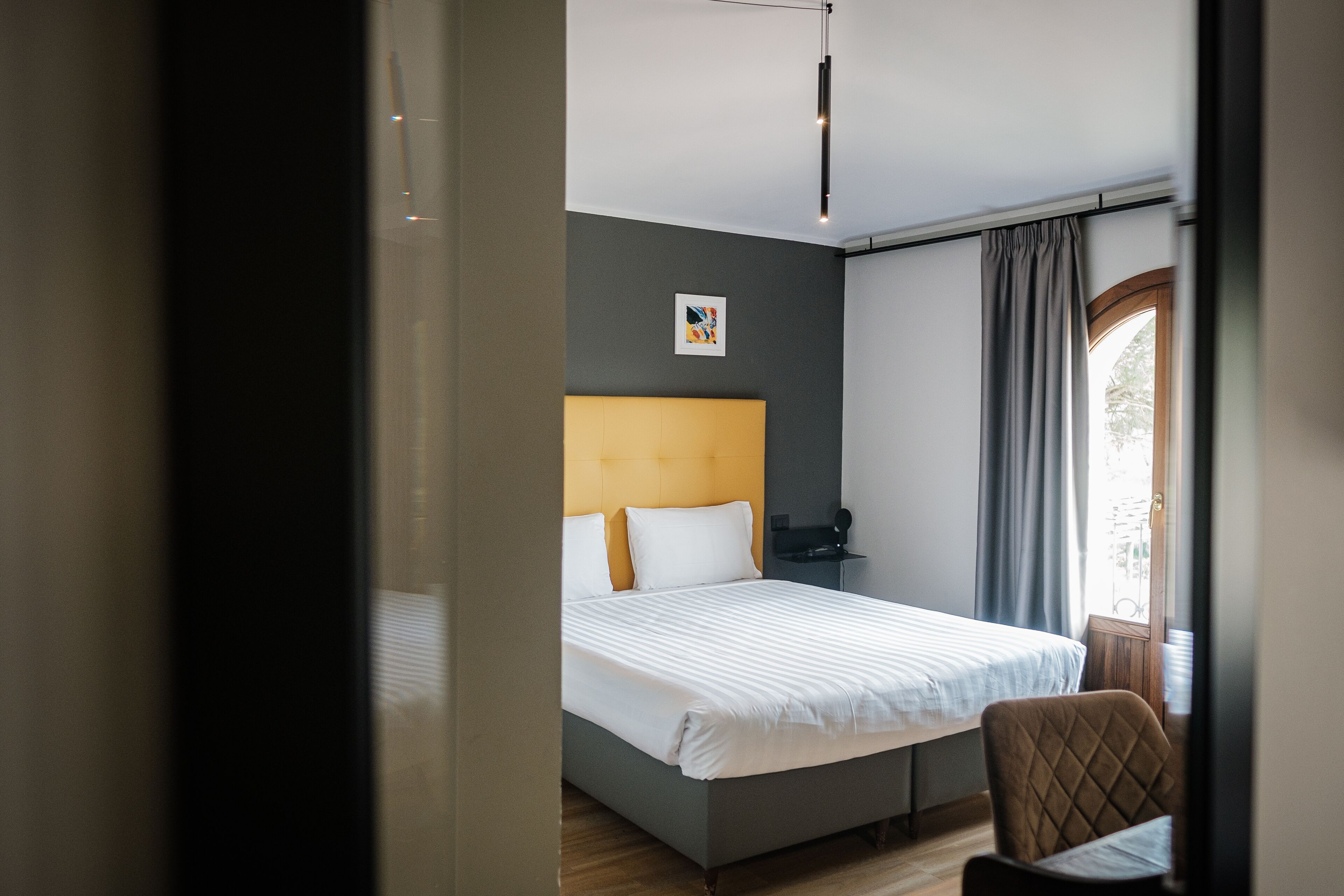 Une chambre d’hôtel moderne avec un grand lit, une tête de lit, une table de chevet et une chaise.