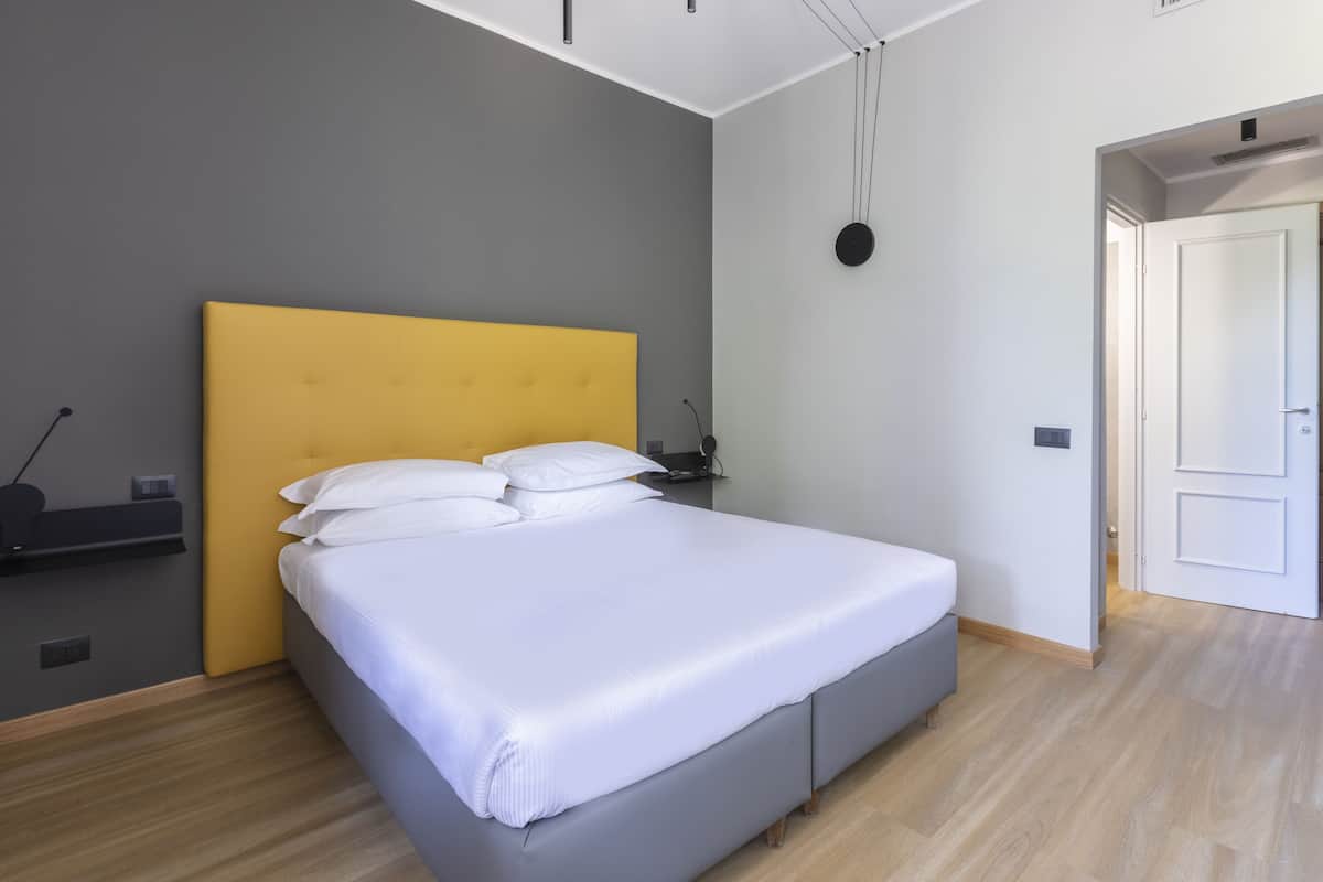 Un dormitorio moderno con cama, mesita de noche y lámpara de pared.