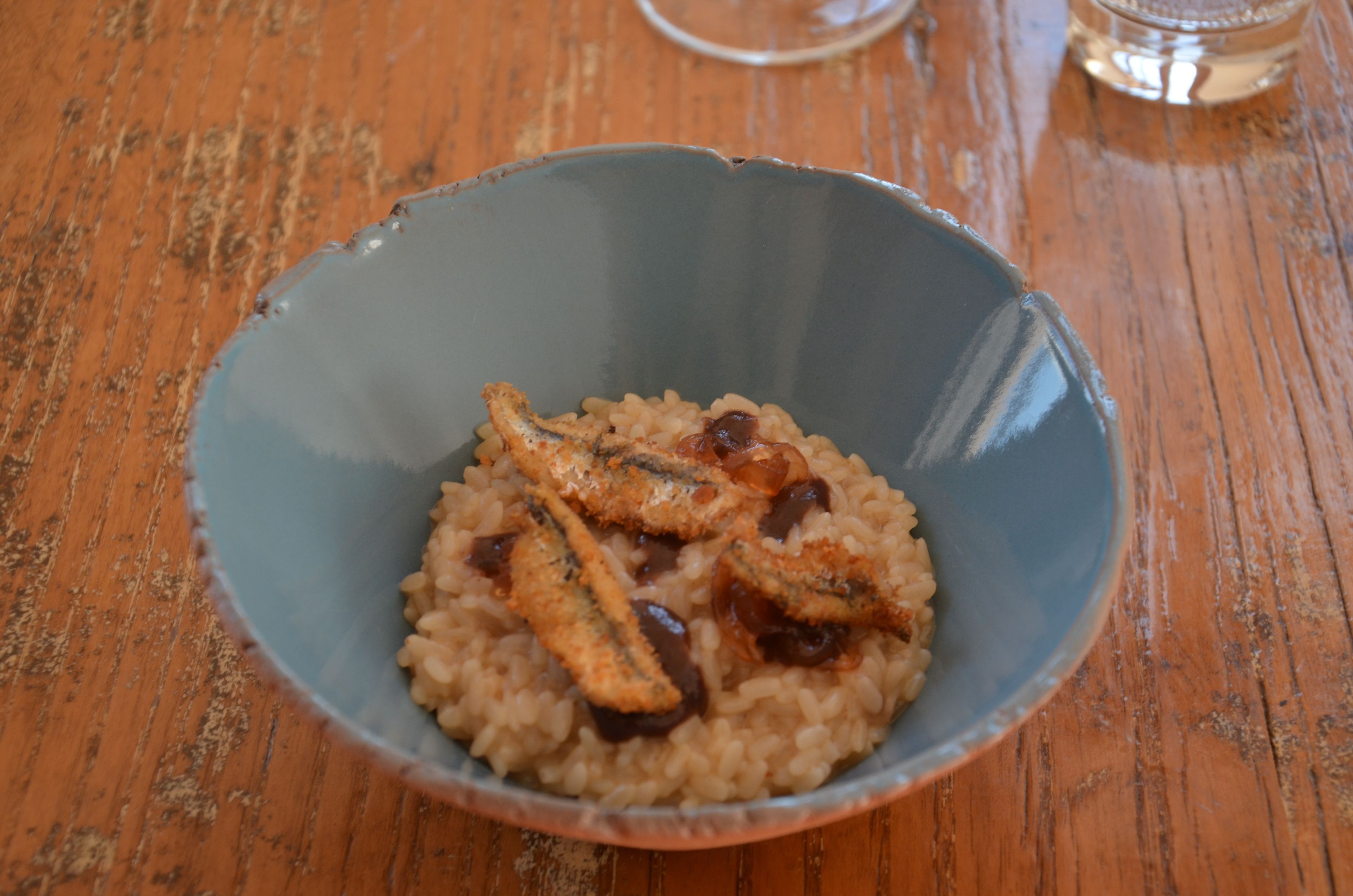 Un bol de riz garni de poisson et de raisins secs, posé sur une table en bois.