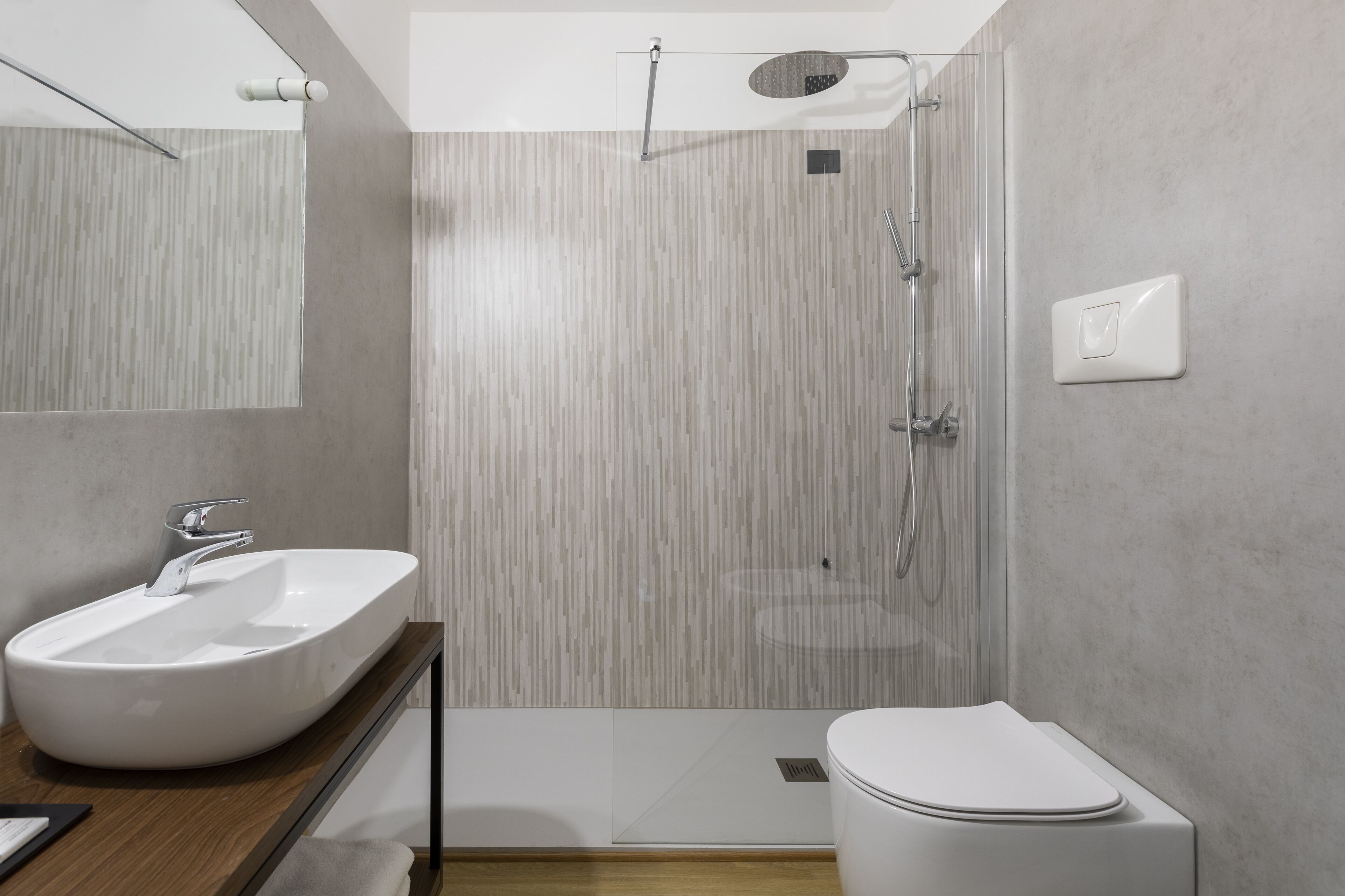 Un baño moderno con un lavamanos grande de color blanco, un inodoro y una zona de ducha.