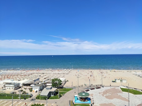 A beach resort with a large sandy area, a small pool, and a stage for events.