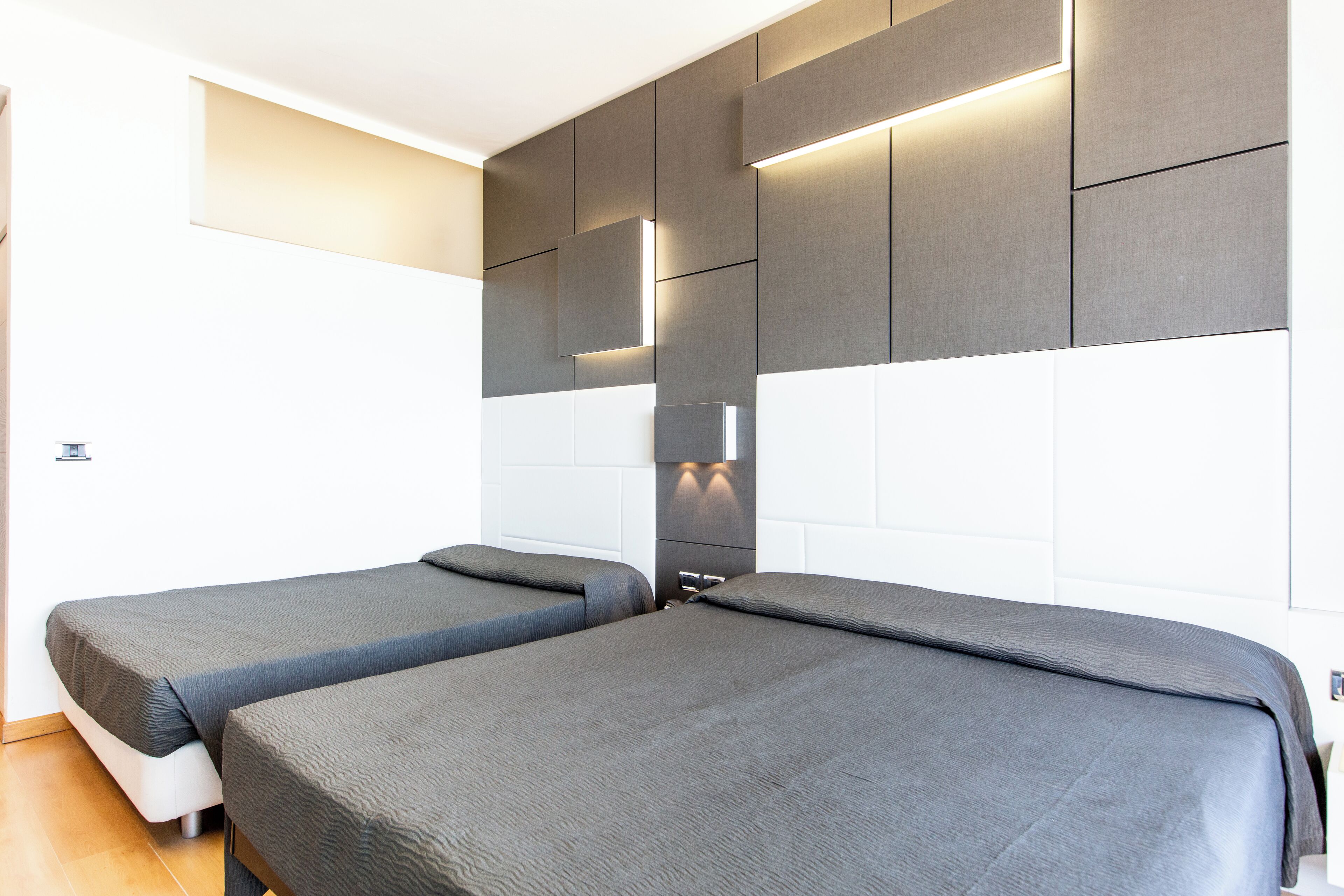Een moderne hotelkamer met twee enkele bedden, een groot raam en een wandlamp.