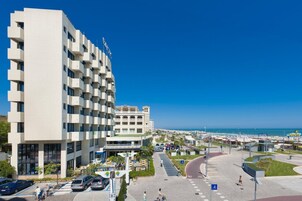 Un hotel moderno con facciata bianca, diversi balconi e vista sulla spiaggia.