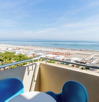 A balcony with a view of a beach and a parking lot.