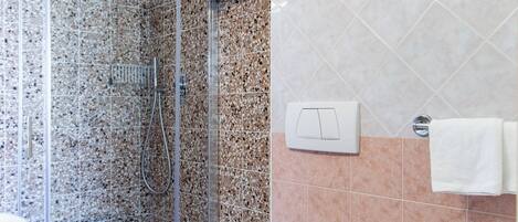 Une salle de bain moderne dotée d’une douche à parois de verre, de toilettes et d’un bidet.