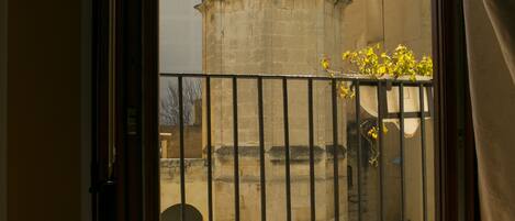 A view through a window of a building with a tower and a barred gate.