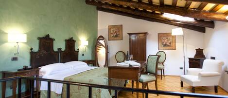 A traditional room with a bed, bedside table, lamp, chair, and wooden ceiling beams.