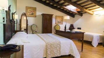 A hotel room with a wooden ceiling, a bed with a white bedspread, a desk with a lamp, and a telephone.