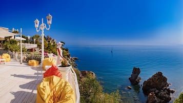 Enjoy a serene coastal view from the outdoor deck with a bathtub and comfortable seating.