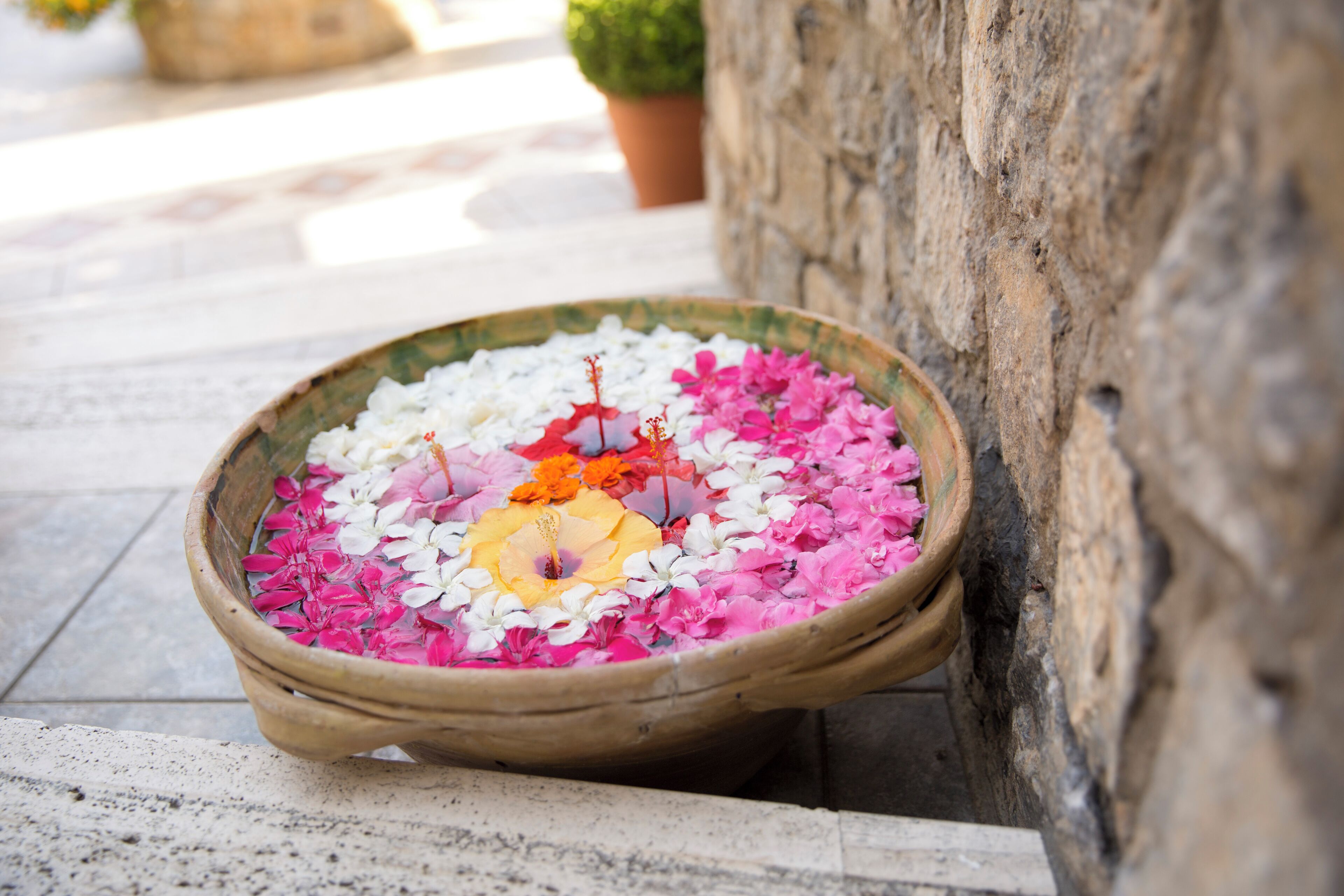 Una bandeja de madera con flores coloridas sobre una superficie de piedra.