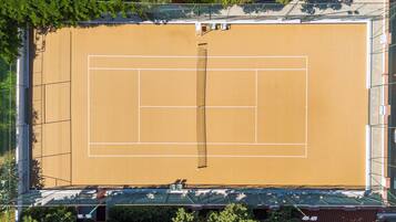 An aerial view of a tennis court surrounded by trees and buildings.