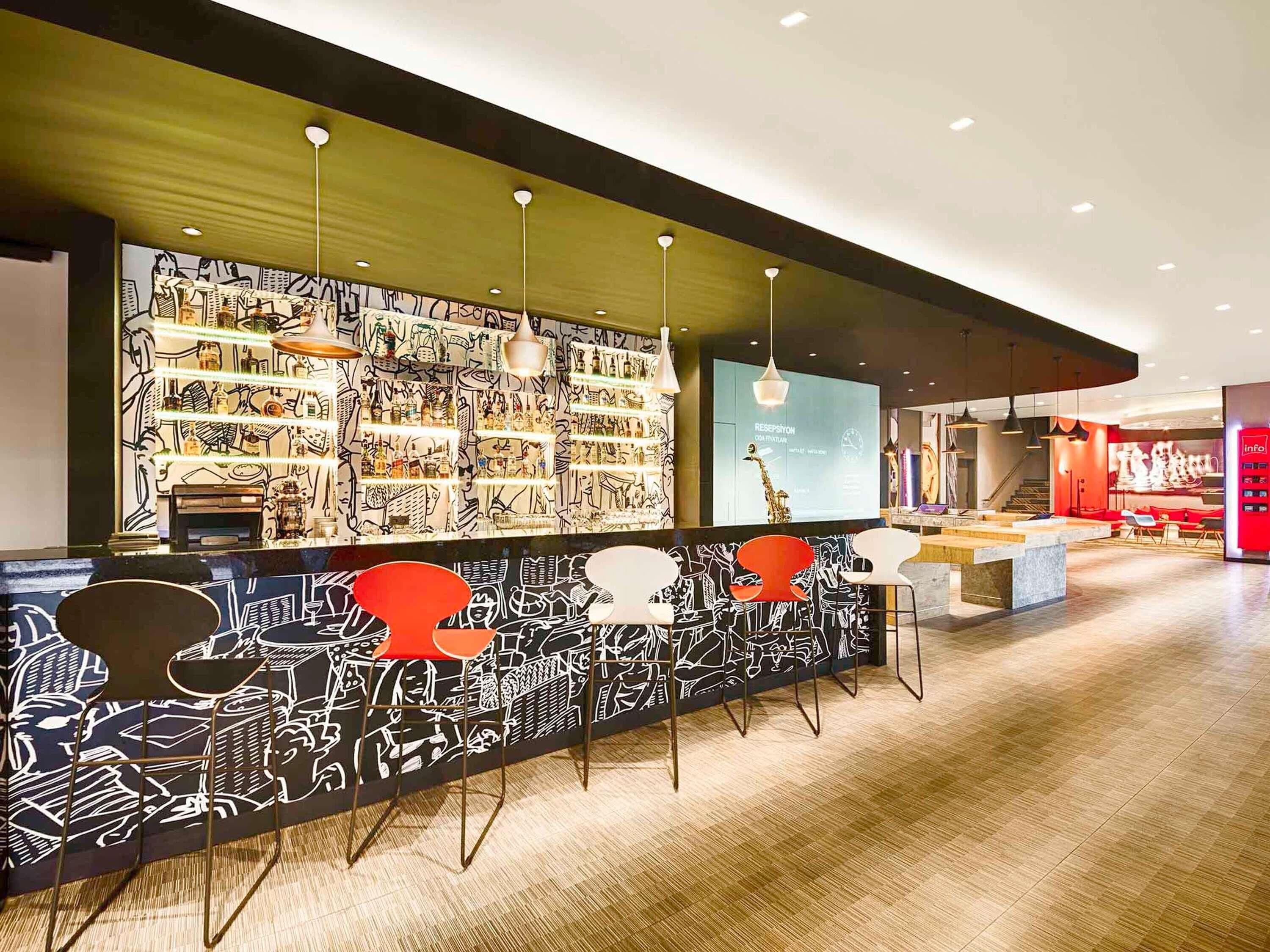 A modern bar area with a patterned wall, hanging pendant lights, and bar stools.
