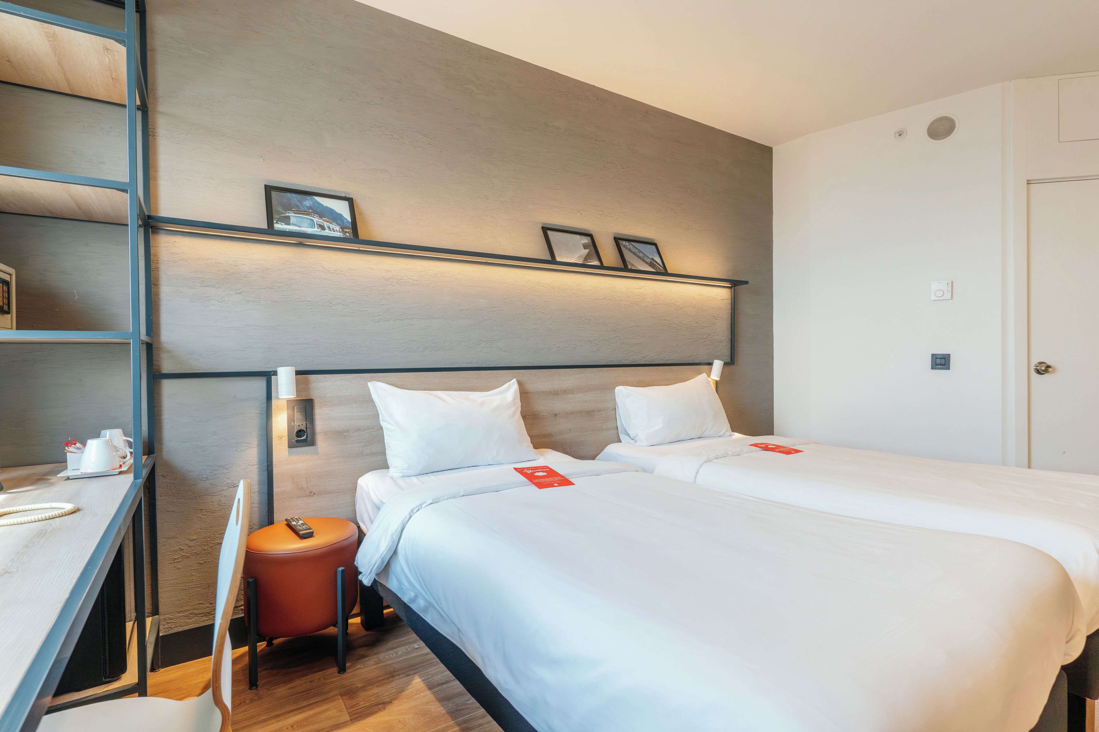 A hotel room with two beds, a desk, and a chair.