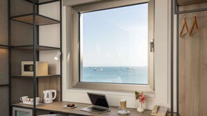 A modern office space with a desk, laptop, coffee maker, and a view of the sea through a large window. - Ibis Istanbul Zeytinburnu (Istanbul)
