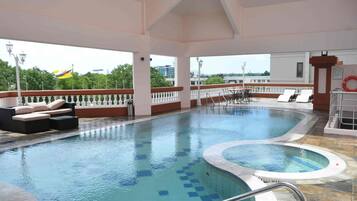 A swimming pool with lounge chairs and a view of the city.