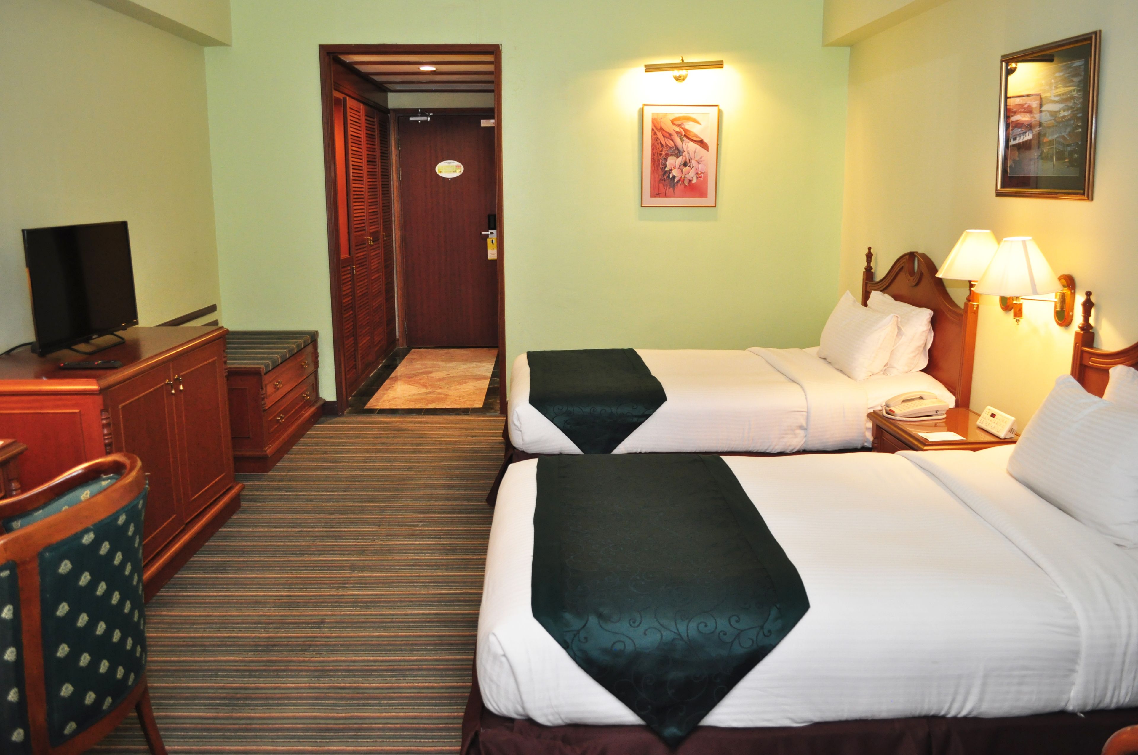 A hotel room with two beds, a television, a desk, and a chair.