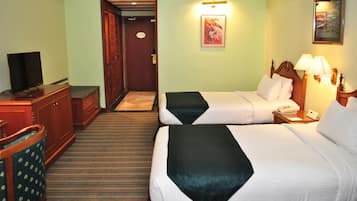 A hotel room with two beds, a television, a desk, and a chair.