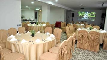 A conference room with round tables, chairs, and a projection screen displaying a waterfall.