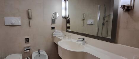 A modern bathroom with a toilet, bidet, sink, and a large mirror.