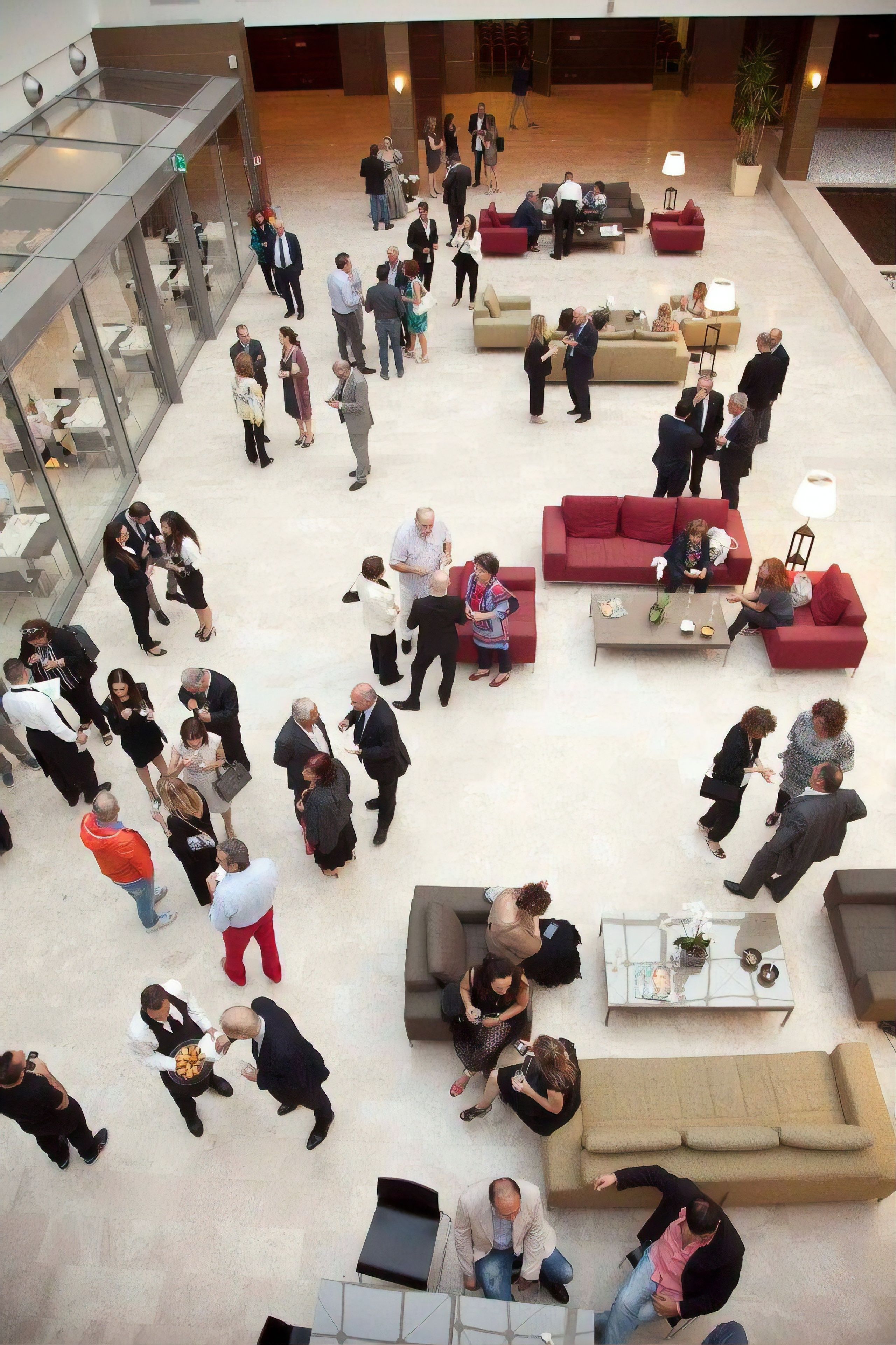 A spacious lobby with multiple seating areas and a glass corridor.