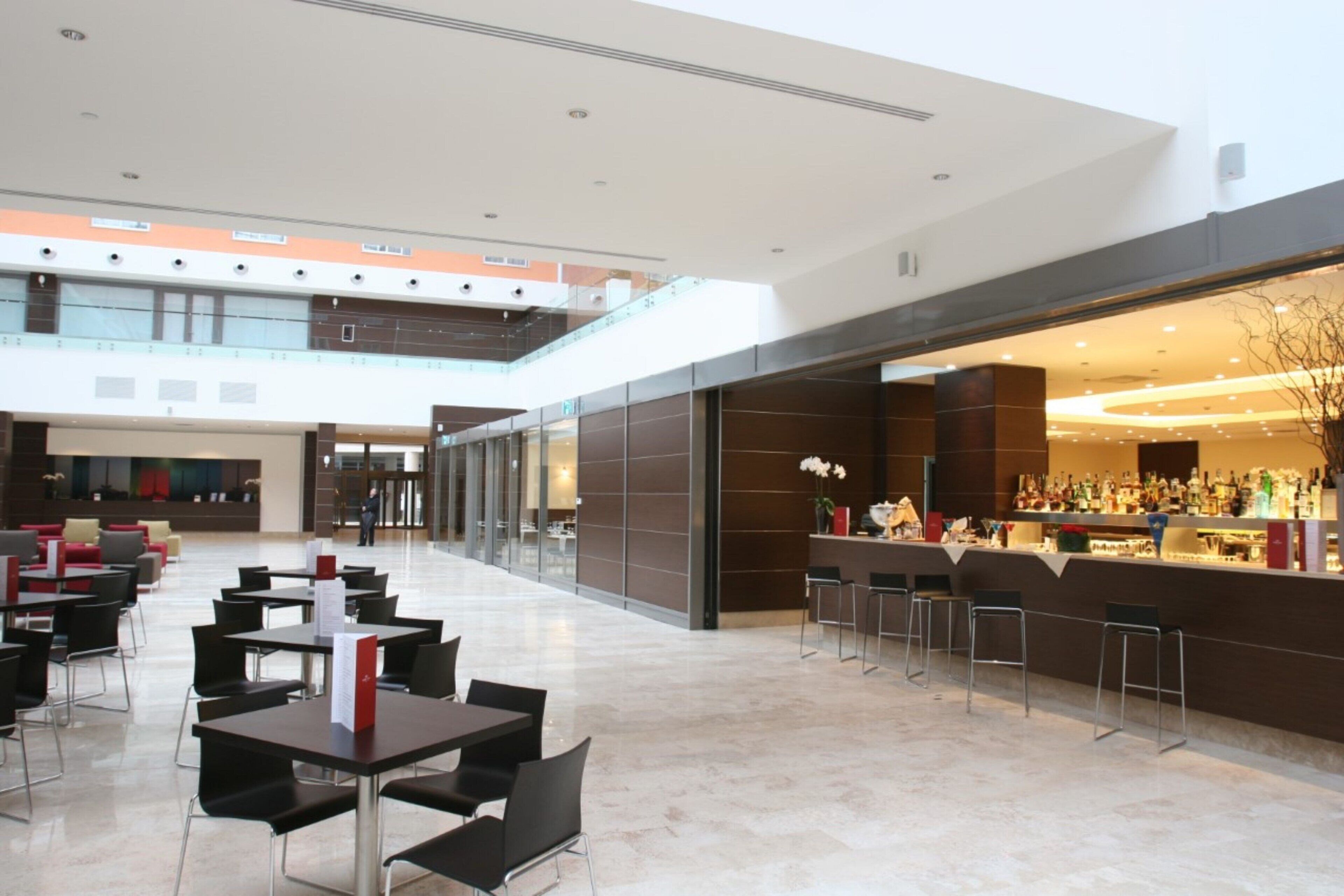 A spacious lobby with a bar area, seating arrangements, and a high ceiling.