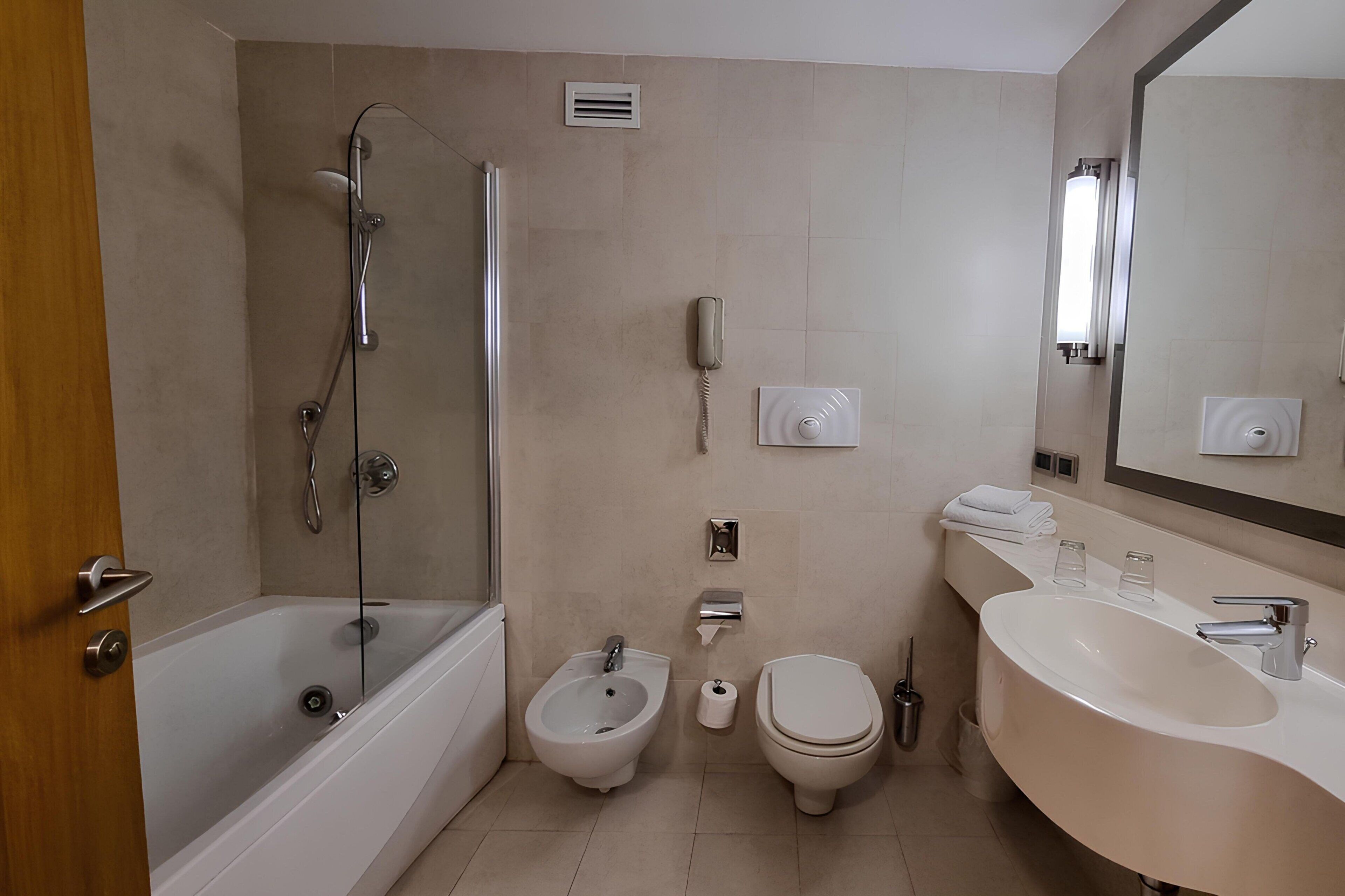 Un bagno moderno con una vasca, una doccia, un bidet, un water e un lavandino con uno specchio sopra.