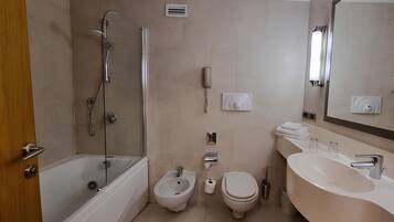 Un bagno moderno con una vasca, una doccia, un bidet, un water e un lavandino con uno specchio sopra.